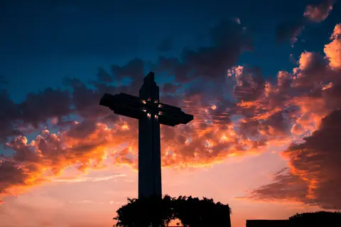 A striking silhouette of a cross with a vibrant sunset in Trujillo, Peru.