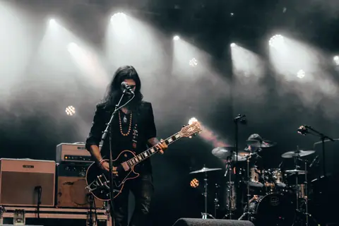 Electric guitarist and drummer performing live on stage at a vibrant rock concert.