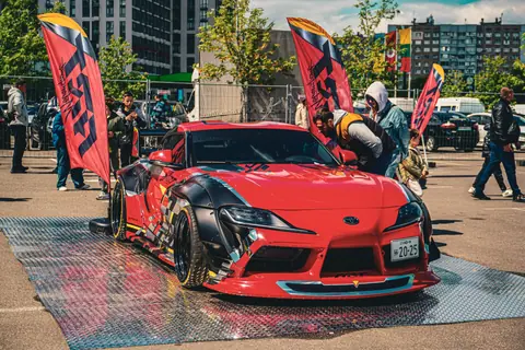 Vibrant red sports car showcased outdoors among enthusiasts at a car exhibition in Kyiv, Ukraine.