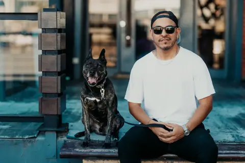 A man in sunglasses with a dog sitting on steps in Buenos Aires, Argentina.
