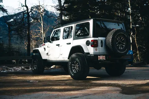 A rugged white SUV parked amidst forested scenery in Jasper, Alberta, Canada.