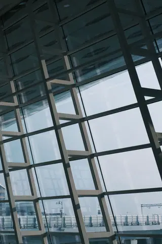 Interior view of a modern airport terminal featuring large glass windows and structural design elements.