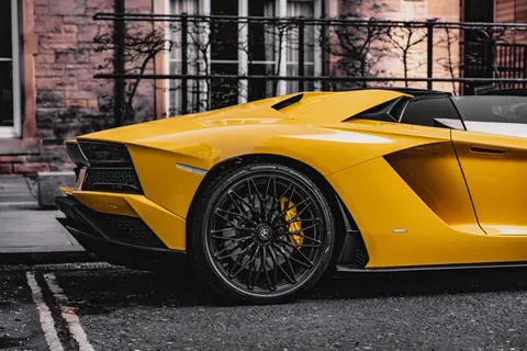 Close-up of a yellow Lamborghini Aventador parked in an urban environment, showcasing luxury design.