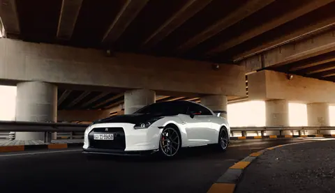 Dynamic shot of a high-performance white sports car parked under a bridge.