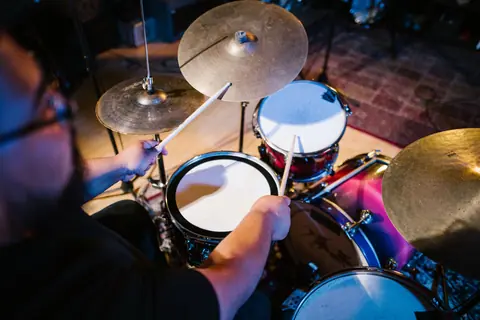 Dynamic close-up of a man playing drums indoors in a music studio.
