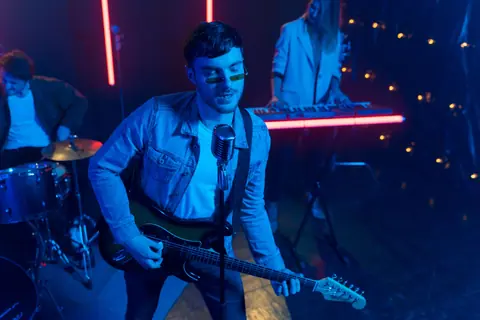 Energetic indie band performing live with vibrant lighting at an indoor venue.
