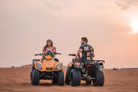 A couple enjoys a thrilling quad bike ride in the desert during a stunning sunset, evoking adventure and exploration.
