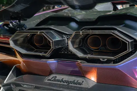 Close-up of a Lamborghini's exhaust system with carbon fiber and metallic accents in Tokyo, Japan.