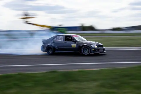 Dynamic shot of a car drifting on a racetrack with smoke trails and blurred motion.