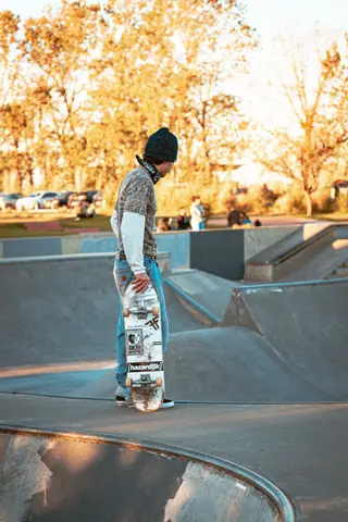 A skateboarder holding a deck at DYD Skate Park in Buenos Aires, Argentina, during a sunny day.