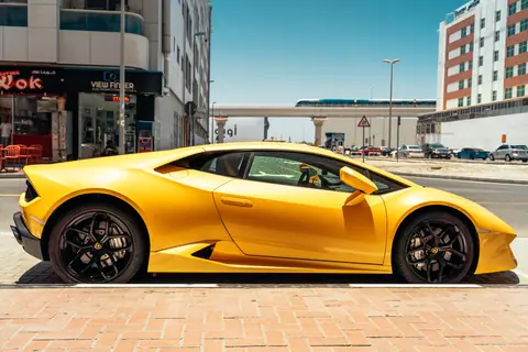 Sleek yellow sports car parked on a sunny day in the vibrant streets of Dubai.