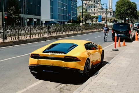A luxurious yellow Lamborghini parked on a street in Istanbul, Turkey, next to a mosque.