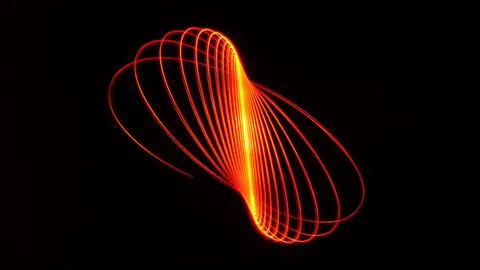 Dynamic abstract light painting featuring red glowing curves on a black background.