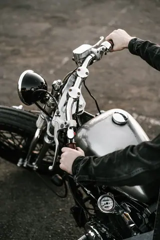 Detailed view of male hands on a vintage motorcycle handlebar outdoors.