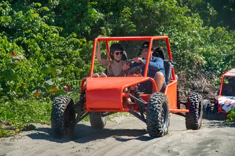Couple enjoying an adventurous ride in a red dune buggy on a sunny day.