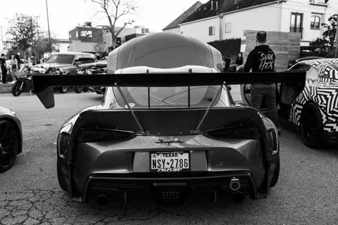 Black and white image of a sportscar parked at a car show with license plate in focus.