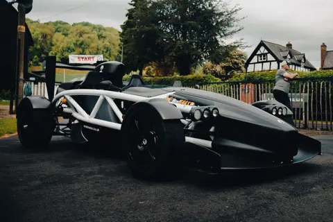 A sleek race car ready at the start line with a countryside backdrop.