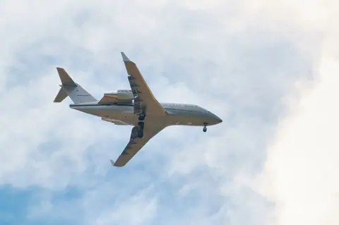 A passenger jet flying against a dramatic cloudy sky, showcasing modern air travel.