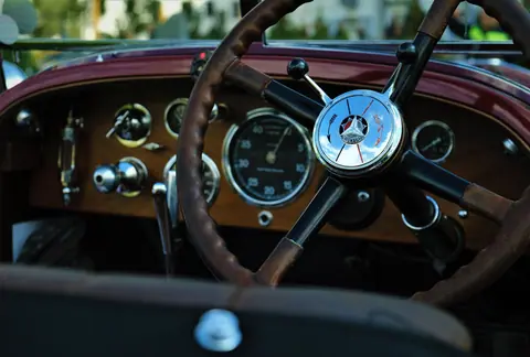 Close-up view of a vintage car's steering wheel and dashboard, showcasing classic design.