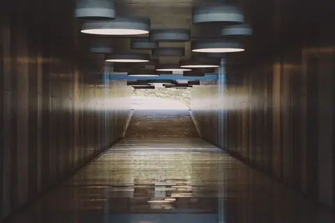 A modern tunnel interior with unique circular lights and reflections on the floor.