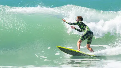 Surfer riding a wave on a sunny day, showcasing skill and adventure.