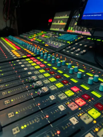 A vibrant and modern audio mixing console in a dimly lit recording studio.