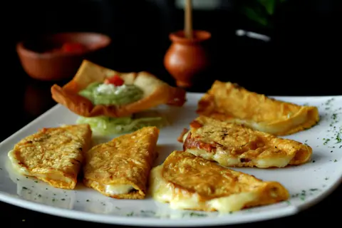 Tasty Mexican quesadillas served with a side of guacamole, making a perfect appetizer or snack.