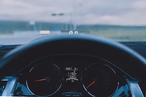 View from inside a car showing dashboard and steering wheel on an open road.