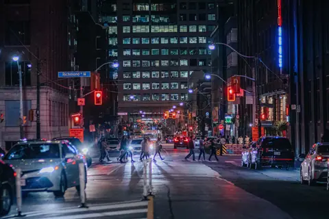 Bustling urban scene on Richmond St at night with people and cars under neon lights.