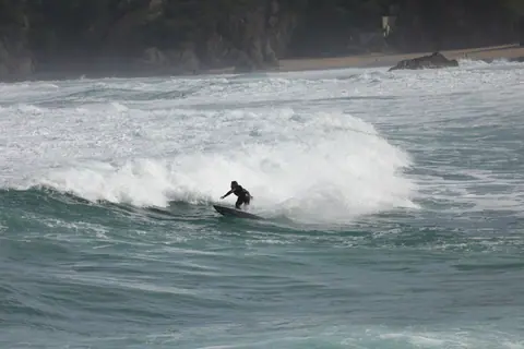 A lone surfer expertly conquers waves at Bakio Beach, Spain, showcasing skill and surfing culture.