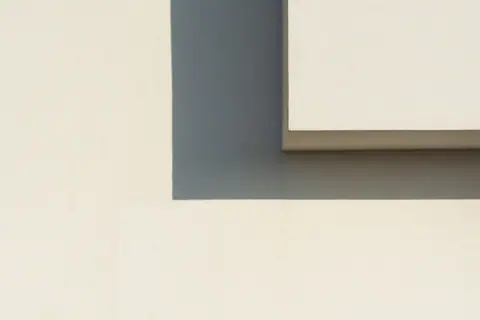 Abstract minimalist image showcasing geometric shadows on a white wall.