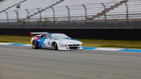 Classic BMW racing car speeding on a racetrack, showcasing motorsport enthusiasm.