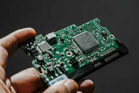 Close-up view of a green circuit board held by a hand, showcasing technology details.