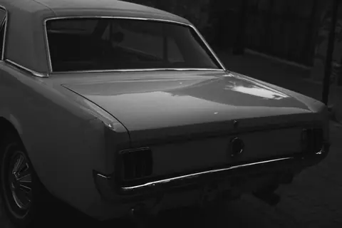Rear view of a classic vintage car in grayscale, showcasing its timeless design.