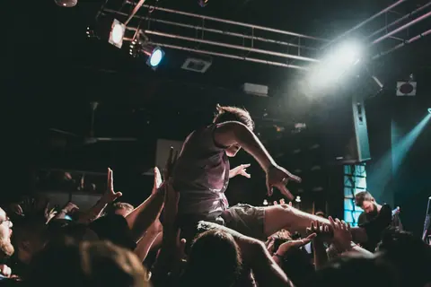 Dynamic scene of crowd surfing at a lively concert performance, capturing the excitement of live music.