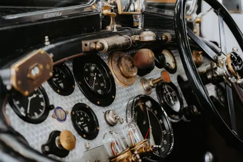 Close-up of vintage car dashboard featuring classic dials and steering wheel, evoking a nostalgic feel.