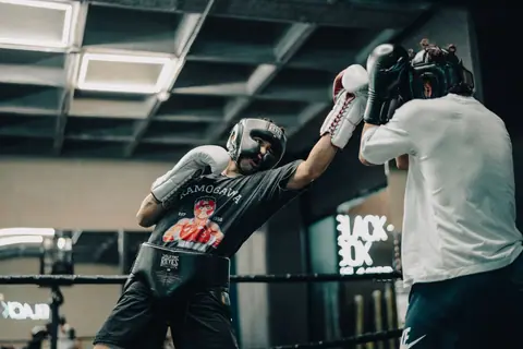 Two boxers sparring intensely in an indoor gym with focus on movement and technique.