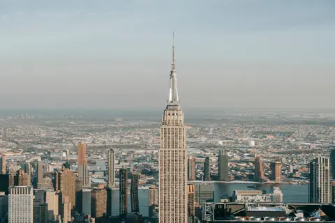 Picturesque skyline of New York City with famous skyscraper with spire and multistory buildings against cloudy sky