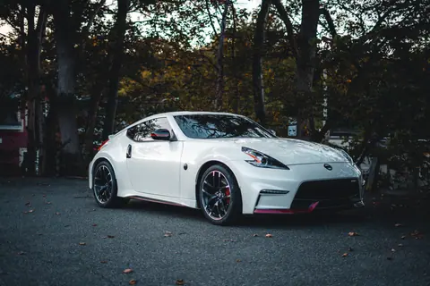 White sports car parked on a scenic road surrounded by trees and nature.