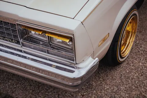 Detailed view of a classic Chevrolet car with gleaming gold rims and chrome bumper.