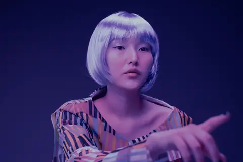 Stylish portrait of a young woman with vibrant dyed hair posing in unique lighting.