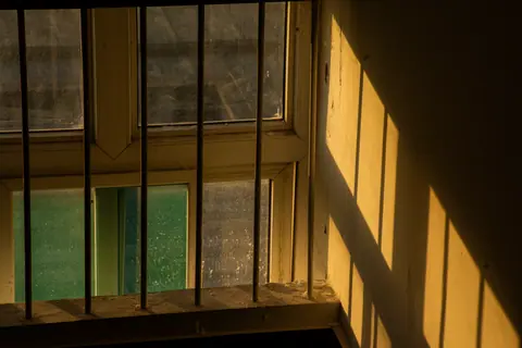 Warm sunset light casting shadows through a barred window.