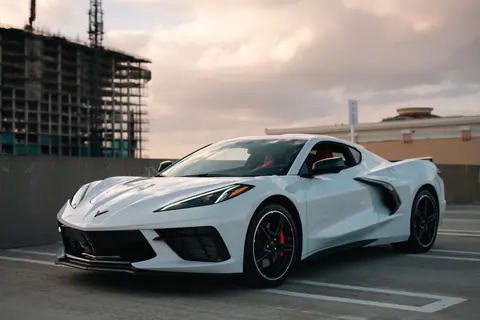 A sleek white Chevrolet Corvette parked outdoors in a modern urban environment with a building under construction.