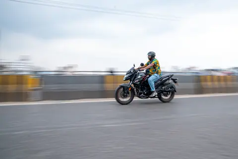 Panning shot of a motorcyclist in motion along a city road, showcasing speed and vibrancy.