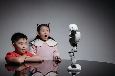 Two children fascinated by a toy robot, showcasing excitement and curiosity indoors.
