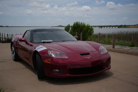 A striking red Chevrolet Corvette parked near a lakeside in Wichita Falls, Texas.