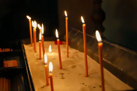 Warm glow of candles on sand in a church, symbolizing peace and reflection.