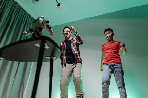 Father and son enjoying a fun dancing session with a robot in their living room.