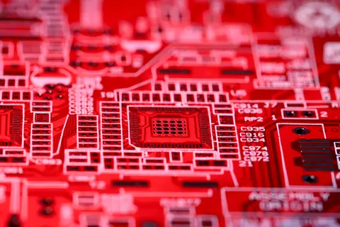 Contemporary red technical circuit board of modern electric machine with various numbers and symbols placed on blurred background in room