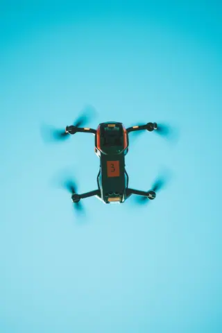 Drone captured from below against a vibrant blue sky showing motion blur.
